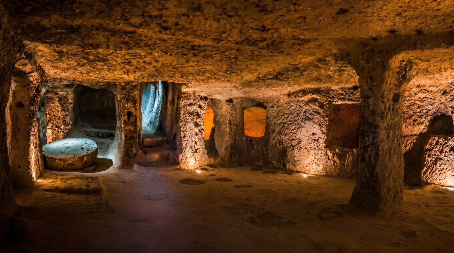 Historic chamber inside Derinkuyu Underground City displaying carved living spaces, stone columns, and atmospheric lighting