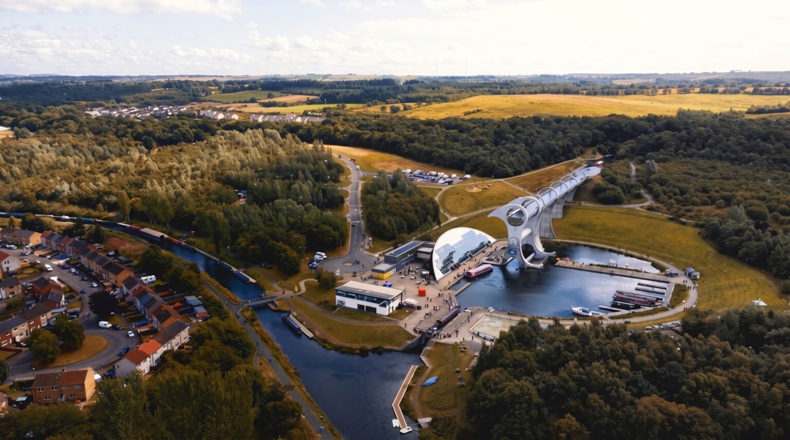 High-altitude aerial drone shot showcasing a rotating boat lift, winding canals, surrounding forests, and a nearby town nestled in the rolling countryside